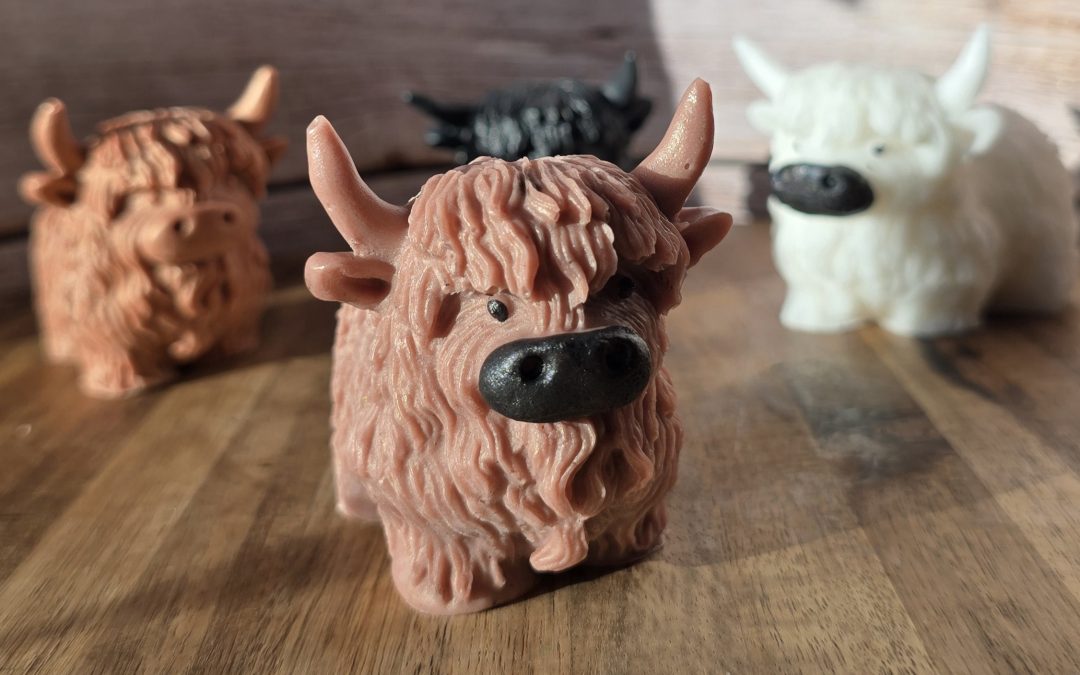 four highland cow soaps, with one positioned at the front and the other three behind - colours, brown, ginger, white and black